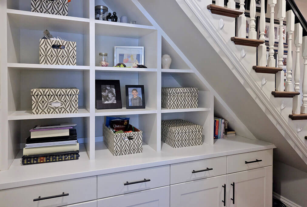 Transforming Space Services with a bookshelf and storage placed under the stairs